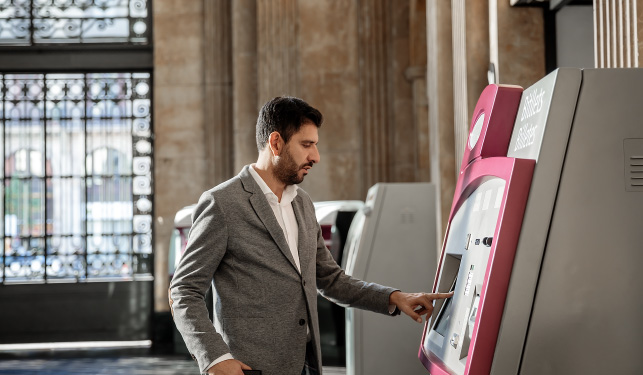 man paying at train ticket machine