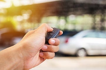 Someone holding a car key up to a car