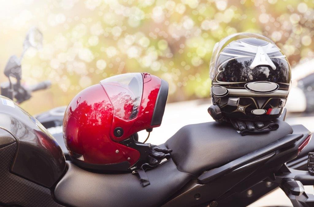 Two motorbike helmets on top a motorbike