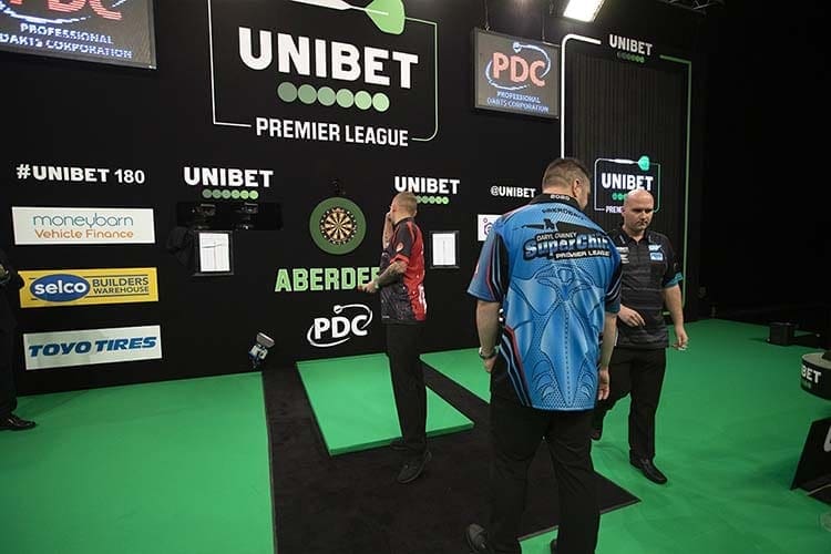 Darts players with the Moneybarn logo behind them