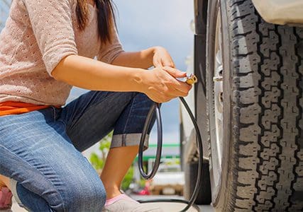 A woman checking tyre pressure