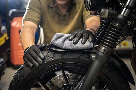 A man checking a motorbike's tyres