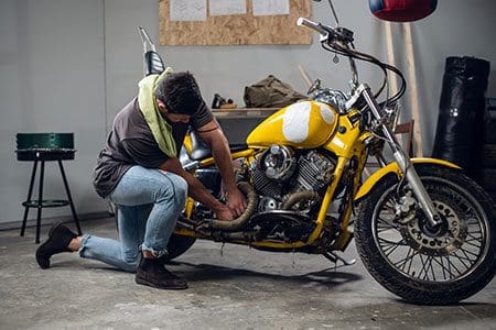 A man storing his motorbike in the garage